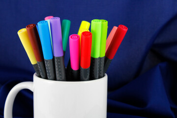 White cup with different colored markers