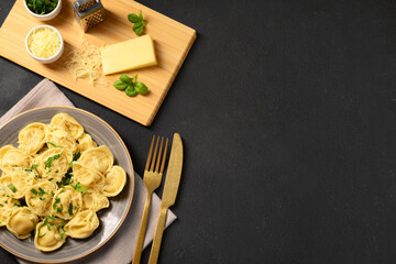 Plate of boiled dumplings with cheese and basil on black background