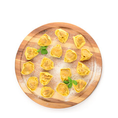 Wooden board with raw dumplings and basil on white background