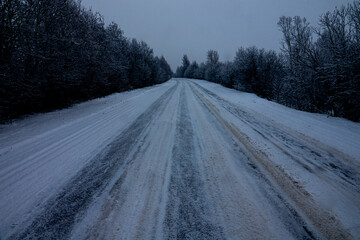 Obraz premium Winter highway The snow has not been removed from the secondary road after the snowfall. Cars have broken through the track, but it is dangerous because vehicle breaking away