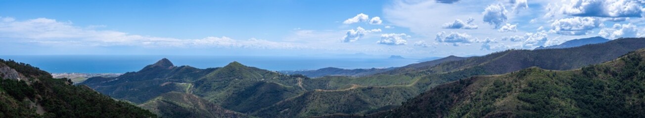 Clouds on blue sky over mountains and sea in Sierra de las Nieves National Park, Andalusia, southern Spain