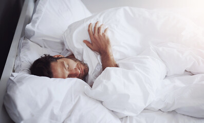 Sleeping, tired and man in bed in home for relaxing on weekend morning with dreaming in rem....