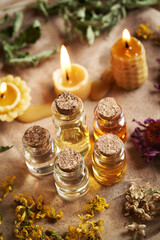 Bottles of aromatherapy essential oils with dried herbs and flowers and beeswax candles