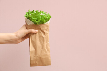 Hand with tasty doner kebab on pink background