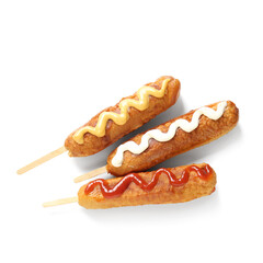 Tasty corn dogs with different sauces on white background