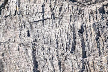 Stone cliff in the mountains, close-up. Natural stone background. Texture of cracks in stone.