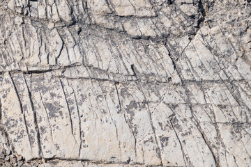 Stone cliff in the mountains, close-up. Natural stone background. Texture of cracks in stone.