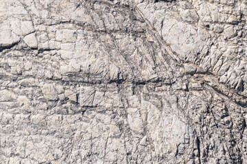 Stone cliff in the mountains, close-up. Natural stone background. Texture of cracks in stone.