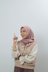 Young woman in hijab in light beige knitted vest top posing dreamily while looking to the side...