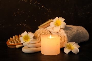 Beautiful spa composition with burning candle and tropical flowers on dark background