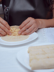 Woman chef preparing tacos, only her hands can be seen rolling a tortilla to make Mexican tacos.