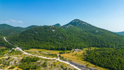 An impressive aerial view capturing the toll booth(Naplatna postaja) on the A6 Rijeka - Zagreb Motorway and the stunning peak of Kamenjak vrh. The motorway, known for its engineering marvels