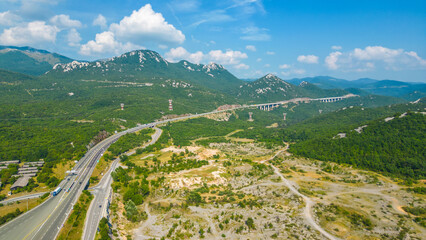 An impressive aerial view capturing the toll booth(Naplatna postaja) on the A6 Rijeka - Zagreb Motorway and the stunning peak of Kamenjak vrh. The motorway, known for its engineering marvels