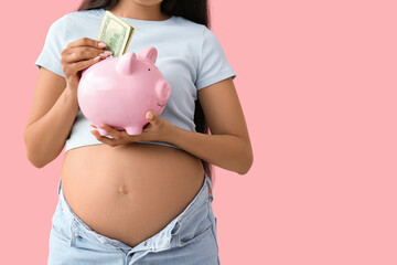 Young pregnant woman putting money into piggy bank on pink background, closeup. Maternal Benefit...