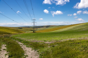 Electricity pylons running through the South Downs, with a blue sky overhead
