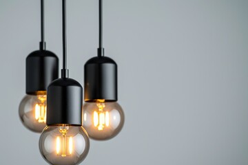 Three black pendant lights with geometric shapes and clear bulbs hang from a ceiling