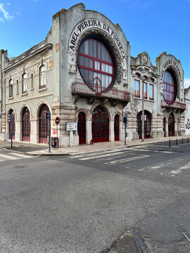 The historic Art Nouveau facade of the old Abel Pereira da Fonseca wine warehouses, now known as the 8 Marvila cultural hub, under a blue sky in Lisbon, Portugal.