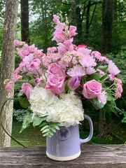 Bouquet of pink roses in a purple pitcher vase