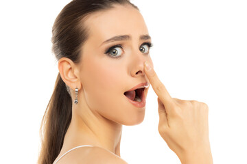 Fototapeta premium young funny woman touches her nose with her finger on a white background