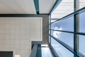 cassette stretched or suspended ceiling with square halogen spots lamps and drywall construction in empty room in house or office with column. Looking up view