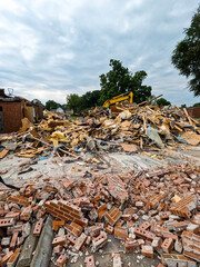 A large brick building has just been demolished. A pile of red bricks, wood insulation and debris...