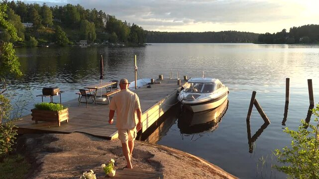 Stockholm, Sweden A man tends to a motorboat on a dock at sunset on Lake Malaren. 