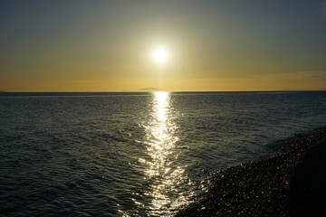 Obraz premium Aerial view to beautiful sunset above wide sea and pebble beach
