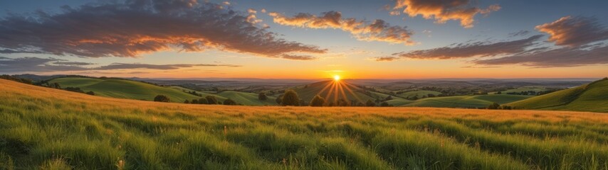 A vibrant sunset casts a golden glow over rolling hills and fields, captured from a low angle to showcase the stunning gradient of colors.
