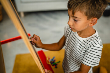 Young boy draw on blackboard whit chalk in the living room