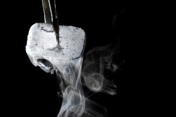 Tweezers holding dry ice block creating smoke