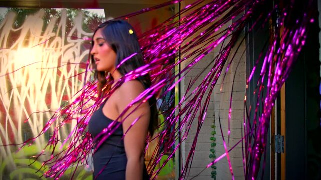 Woman walks through pink shiny party streamers