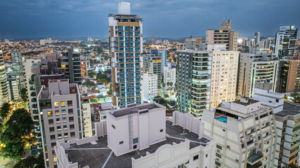 Fototapeta premium Vista aérea noturna do bairro Cambuí na cidade de Campinas, interior de São Paulo. Vários prédios residenciais e luzes da cidade com céu nublado.