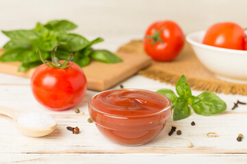 Delicious ketchup with spices and tomatoes on wooden table