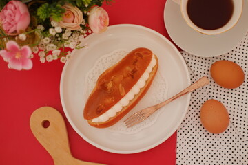 Eclair with coffee and eggs on red background, top view.