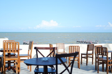 Empty tables and chairs in a restaurant on the beach with sea background