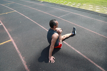 Athlete On A Racing Track Stretching After The Run 