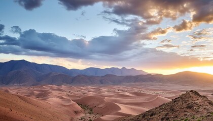 Fototapeta premium Cloudy sundown sky over hills and rocks in arid desert in evening in Morocco 