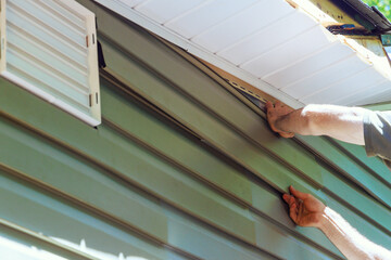Obraz premium Construction employee installs vinyl plastic siding panels on new house wall facade