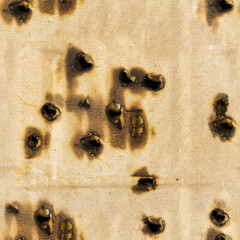 Seamless 4k photo texture of burned and perforated cardboard paper surface.
