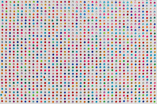 Multicolored rhinestones close-up on a white background. Preparation for the holiday. Children's handicrafts as a way of development and relaxation.