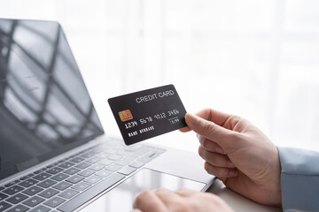 Businessman securely enters payment details online with a credit card and laptop, showcasing the convenience of e commerce in today's digital age