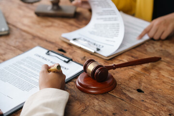 Lawyers discussing contract with gavel on table, serious atmosphere, focused on document,...
