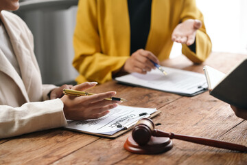 Lawyers discussing contract in office, with gavel symbolizing justice. Collaborative teamwork,...