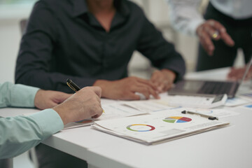 Business people are reviewing financial reports and analyzing charts during a meeting, demonstrating teamwork and collaboration in the workplace