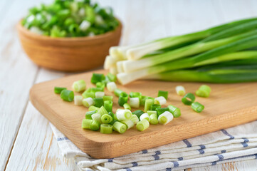 Heap of chopped green onion on a wooden cutting board , selective focus.