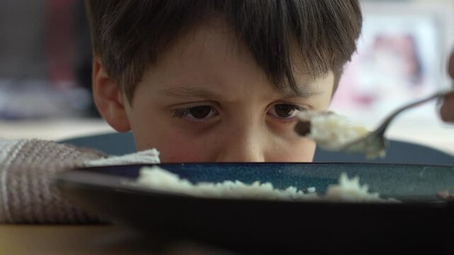 Young boy reluctantly eating rice while being fed by a parent displaying a range of emotions from hesitation to acceptance captured in a sequence of close-up shots highlighting family mealtime dynamic