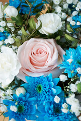 delicate pink rose in a bouquet with blue chrysanthemums and white carnations
