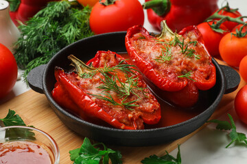 Tasty stuffed peppers in dish and ingredients on white table