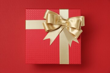 Gift box with bow on red background, top view