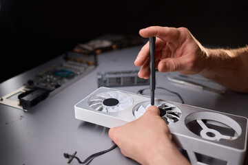 A technician is skillfully repairing a computer GPU fan with precision tools in a workshop
